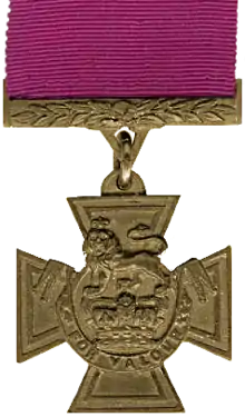 A bronze cross pattée bearing the crown of Saint Edward surmounted by a lion with the inscription 'FOR VALOUR'.  A crimson ribbon is attached.