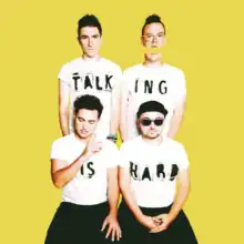 The band members of Walk the Moon wear white t-shirts that spell out Talking Is Hard in front of a yellow backdrop.