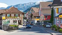 A busy street in a small town. The mountains are visible above the rooftops.