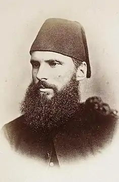 Formal photo of a young, bearded man in a fez