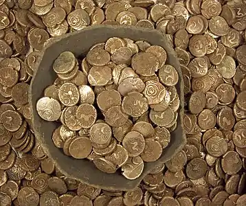 Pot filled with coins surrounded by many more