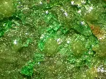 A transparent bright green mineral intermingles with a transparent yellow-green mineral.