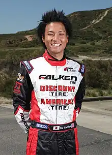 Colour photo of Dai Yoshihara smiling widely and wearing his racing gear