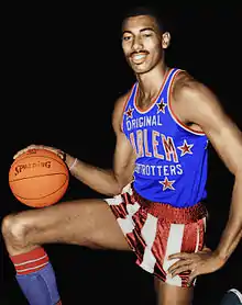  Man in a Harlem Globetrotters uniform is on one knee and holding a basketball.