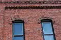 Brick corbelling and dentillation above two windows