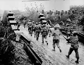 United States Army troops passing through dragon's teeth on the Siegfried Line in 1944.