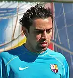 short haired man, in blue football shirt, In the background, there i football nets.