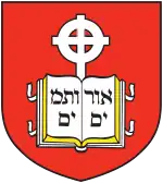 Coat of arms of the school, containing a book device inscribed with Hebrew letters and cross in front of a red background