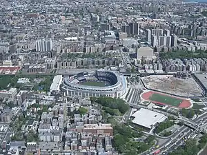 Yankee Stadium (center); Bronx County Courthouse and the Grand Concourse (towards the top); and the site of Yankee Stadium's predecessor to the far right. View is from the northwest, looking to the southeast, with Rikers Island and Queens visible in the upper right corner.