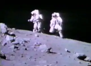 Astronauts Charles Duke (right) and John Young, walking back to the Lunar Roving Vehicle from the blocky rim crater at Station 4