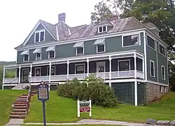 A green and white house with peaked roofs and awnings